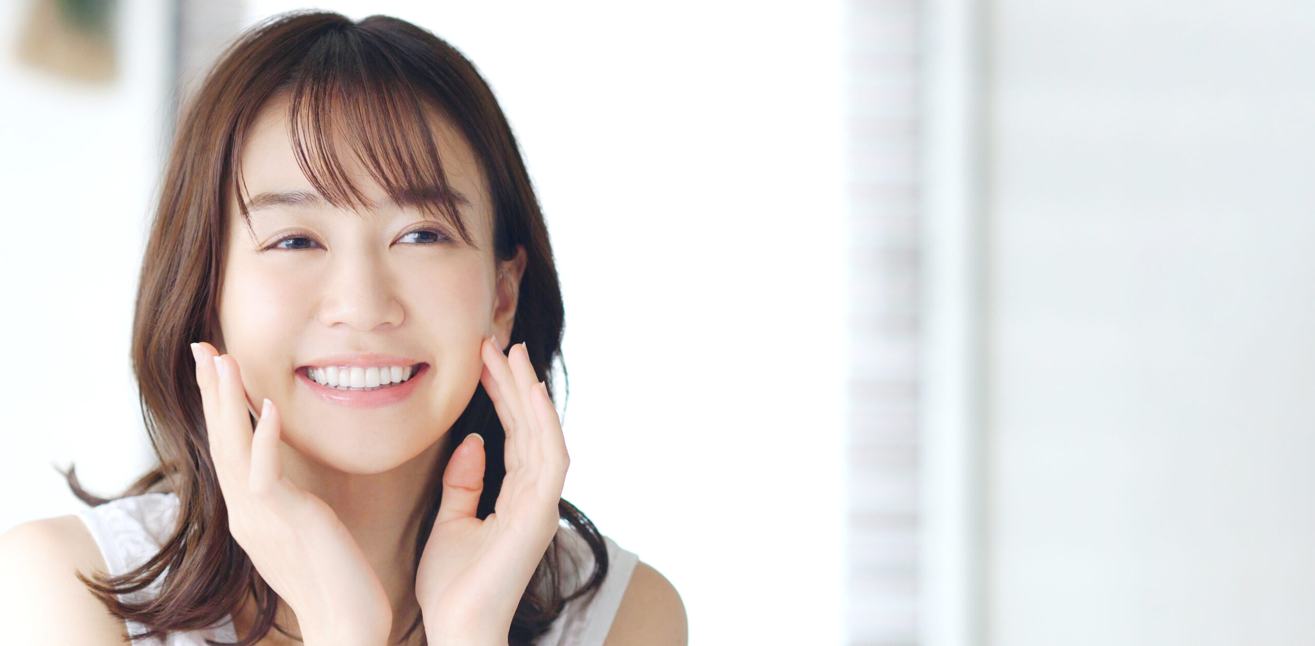 口元に手をあて歯を見せて笑顔の女性
